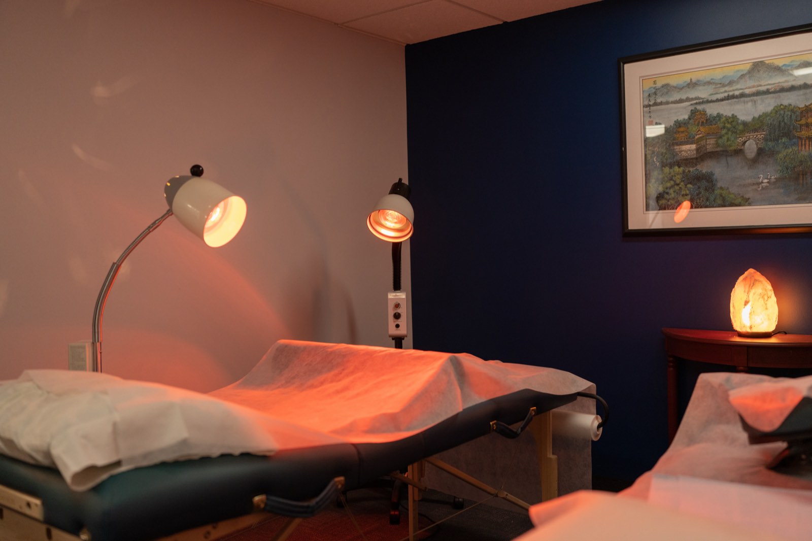 Softly lit treatment room with a glowing salt lamp and framed artwork