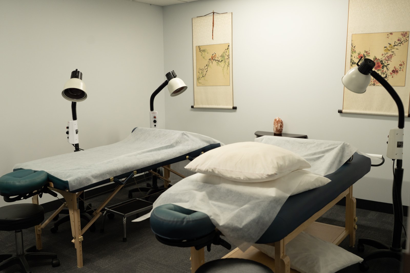 Private treatment room with two treatment tables, heat lamps, and traditional scroll paintings
