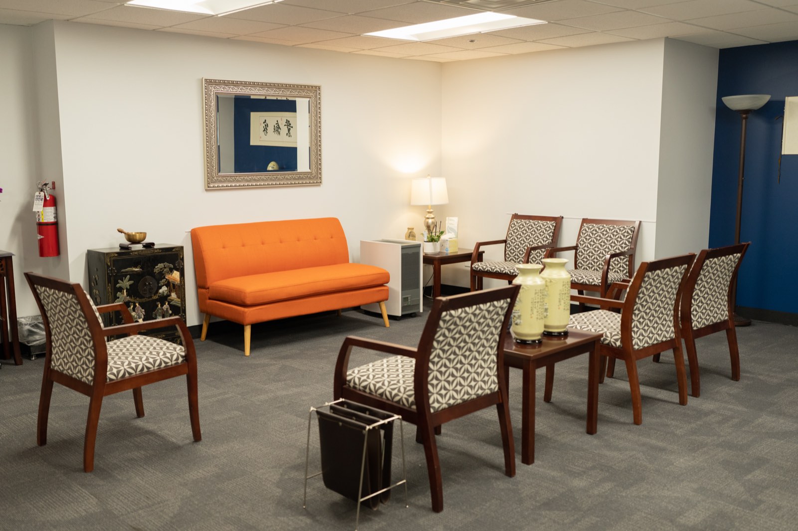 Waiting room with an orange sofa, armchairs, and warm lighting